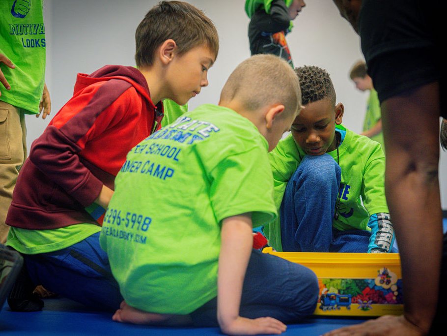 Three boys kneeling on the mat around a big bin of building blocks during toy time